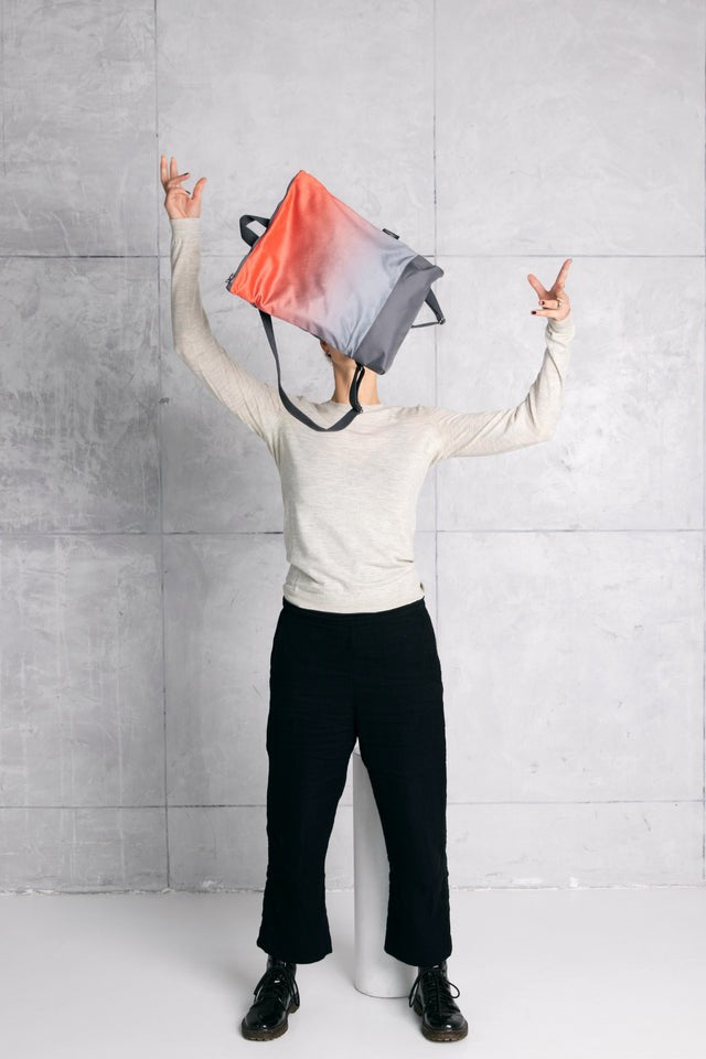 playful salmon faux leather backpack held by a woman in a sunlit park