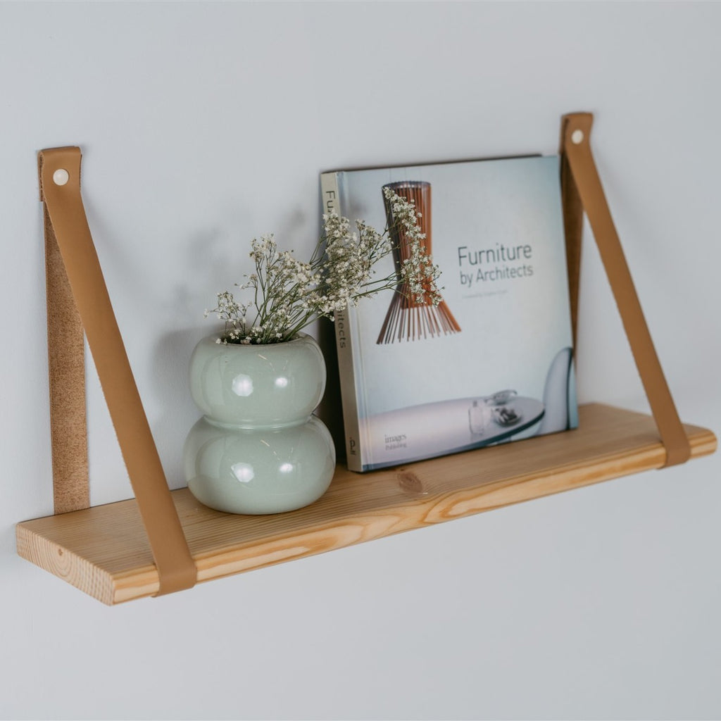 bold 70 cm floating pine shelf with camel leather straps in dramatic studio light