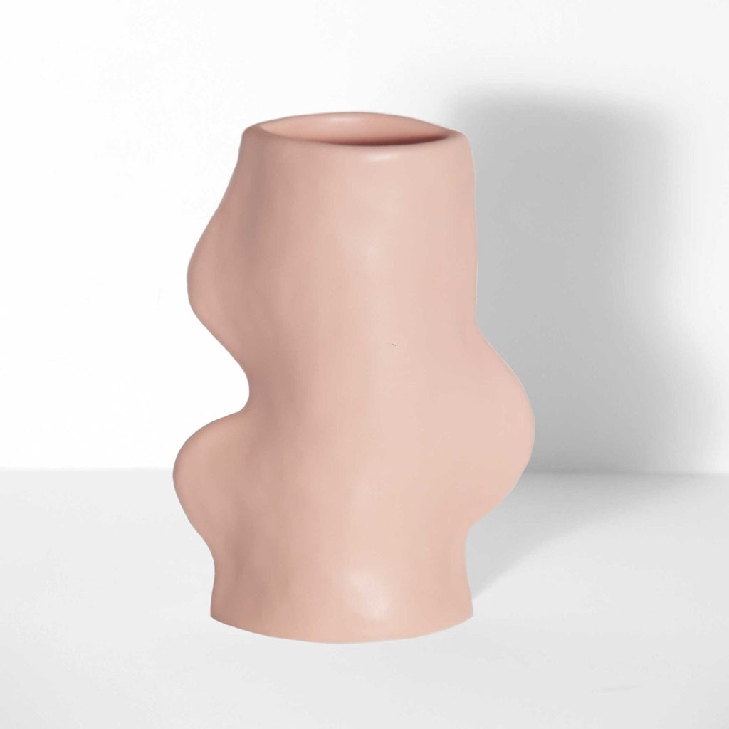 soft pink ceramic fluxo vase on a cozy tabletop, its flowing curves glowing in warm morning light