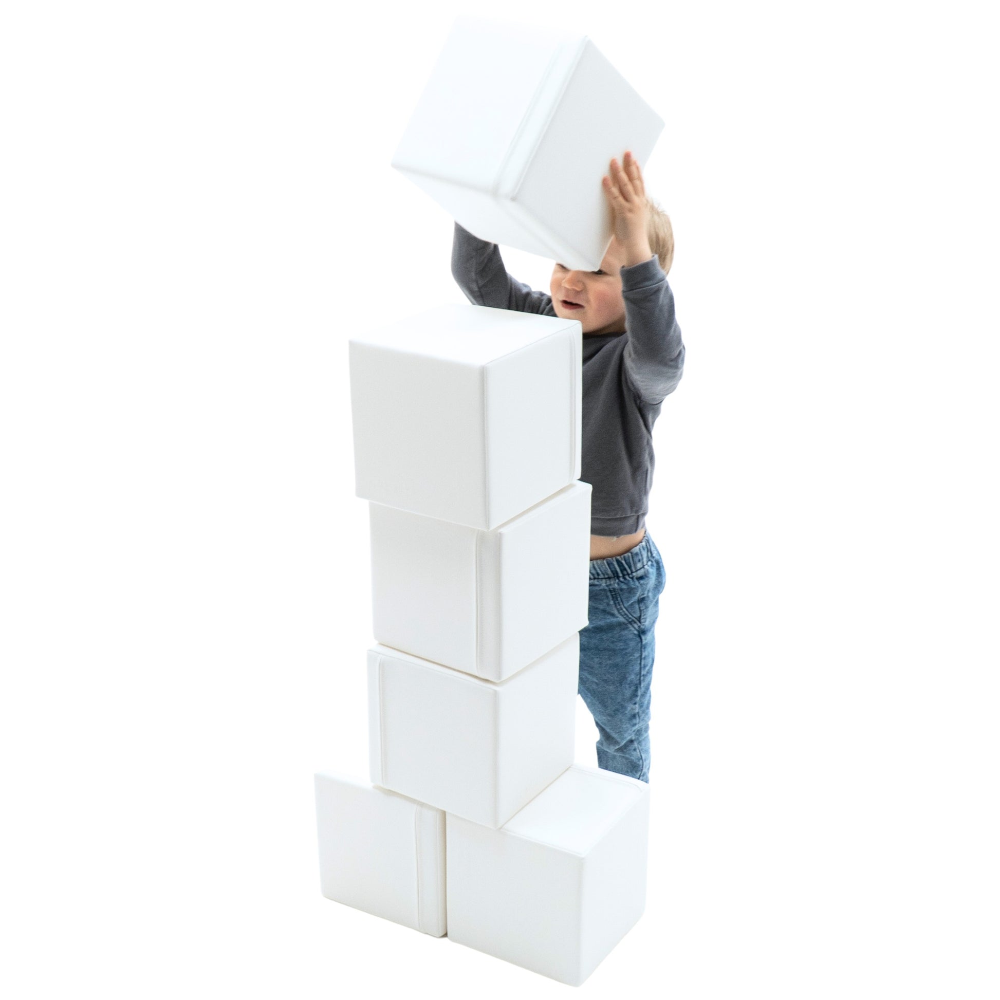 confident toddler building a tall igloo from soft foam blocks