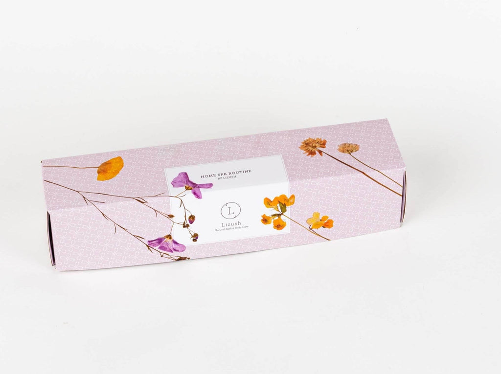 a playful arrangement of the lizush spa gift set with the clay mask pot open and a brush resting on top