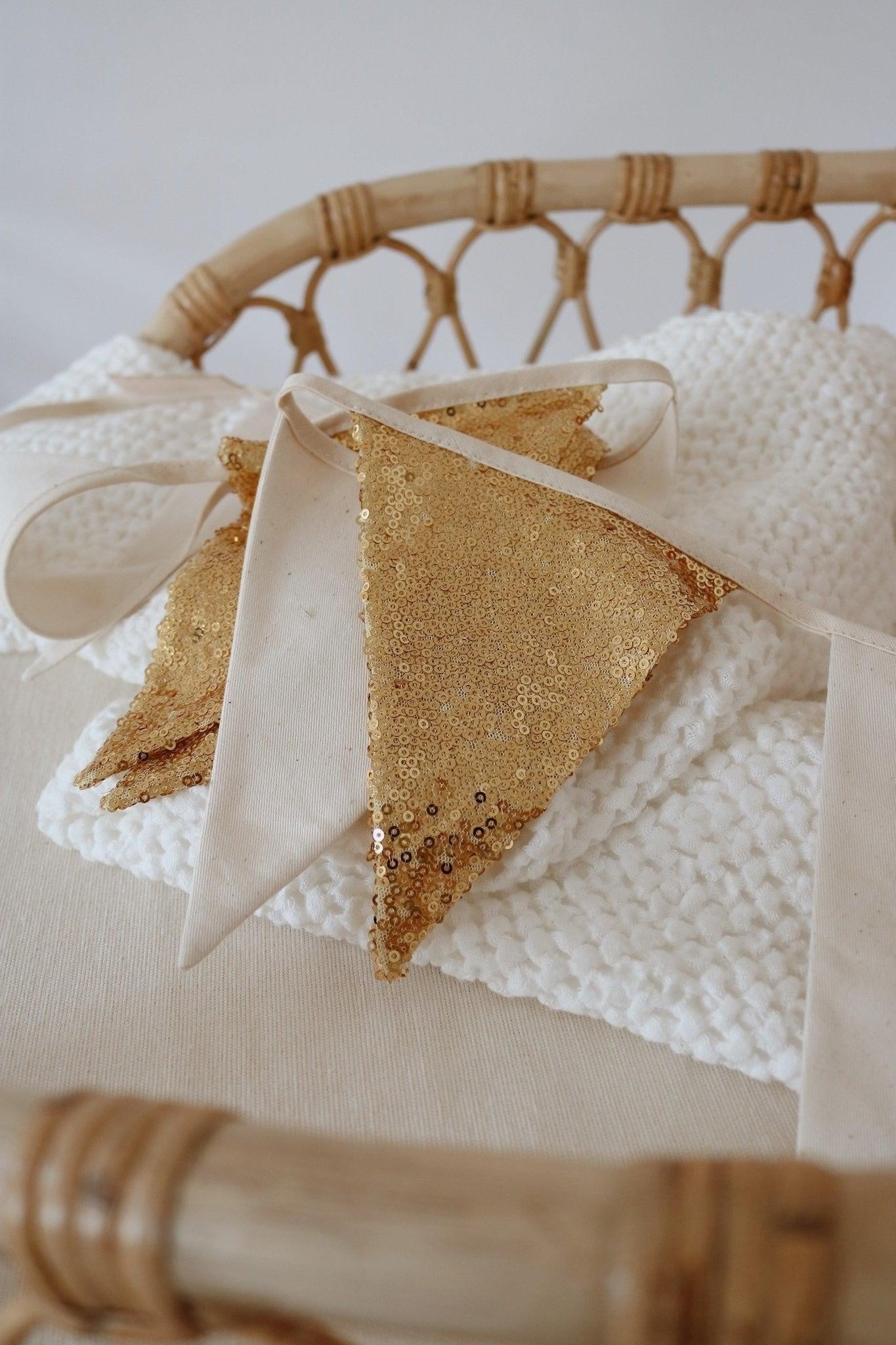 gold and beige sequin garland draped over a wooden crib, catching soft morning light for a dreamy nursery touch