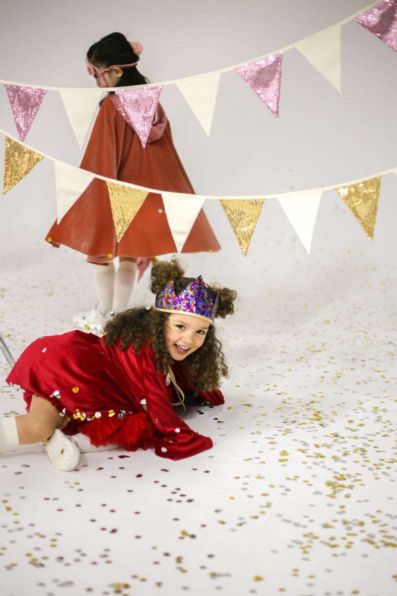 bold pink and beige sequin garland cascading over a wooden crib in a child's room