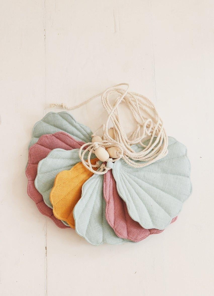 softly lit linen shell garland with mint pink and mango tones draped over a cozy reading nook
