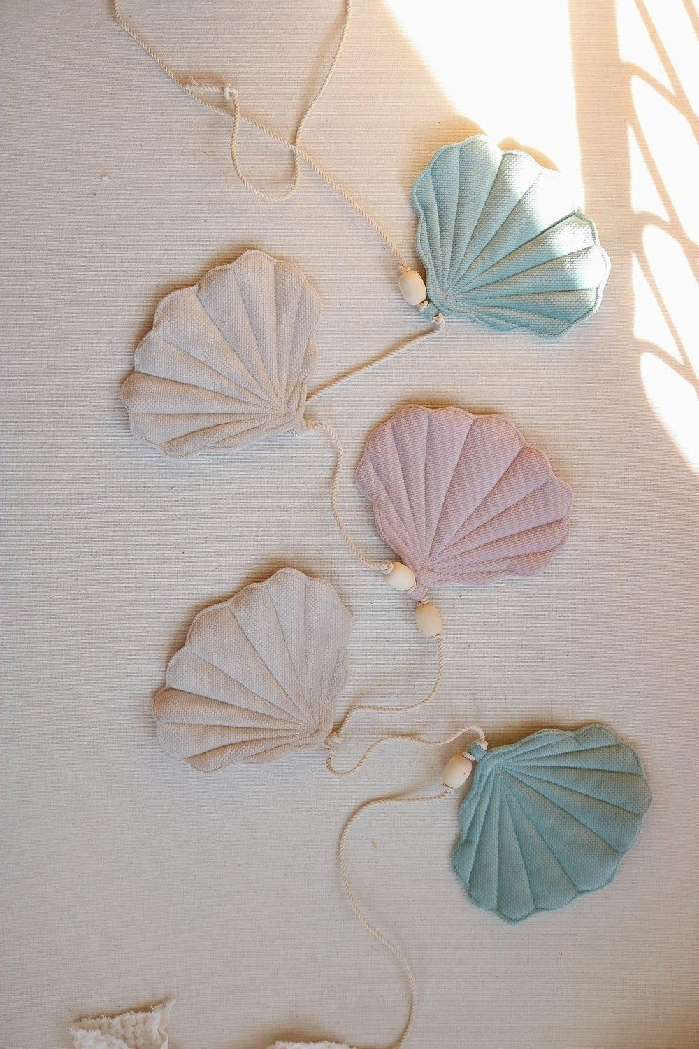 playful shell garland with velvet pendants and wooden beads, dangling in a sunlit child's room for summer magic