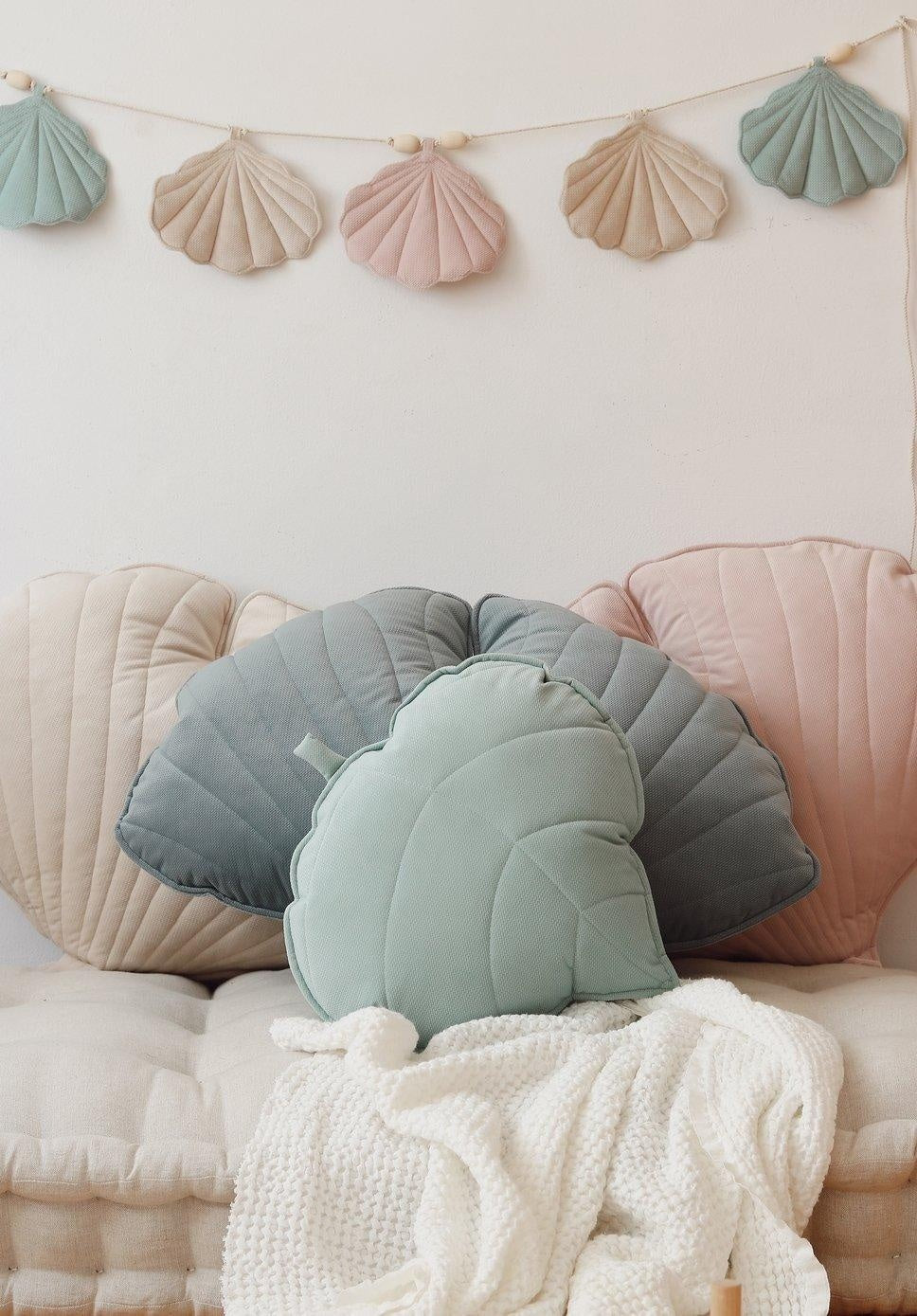 shell garland in late summer light, hung on a wooden bead string, practical decor for kids' rooms or garden tents