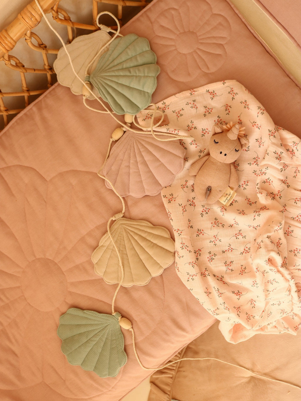 shell garland draped over a rustic wooden crib, soft summer light highlighting velvet pendants and wooden beads