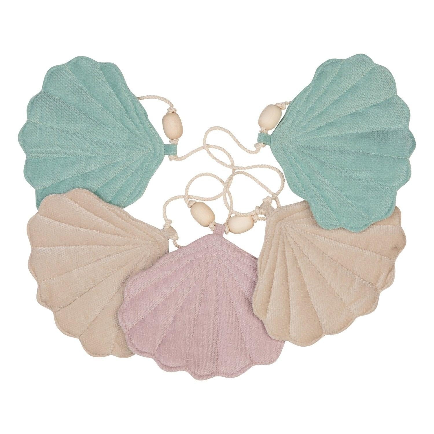 softly lit shell garland with velvet pendants and wooden beads, draped elegantly over a rustic window frame