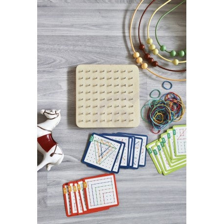 a child's hands creating a geometric star shape on the green wooden geoplan puzzle board