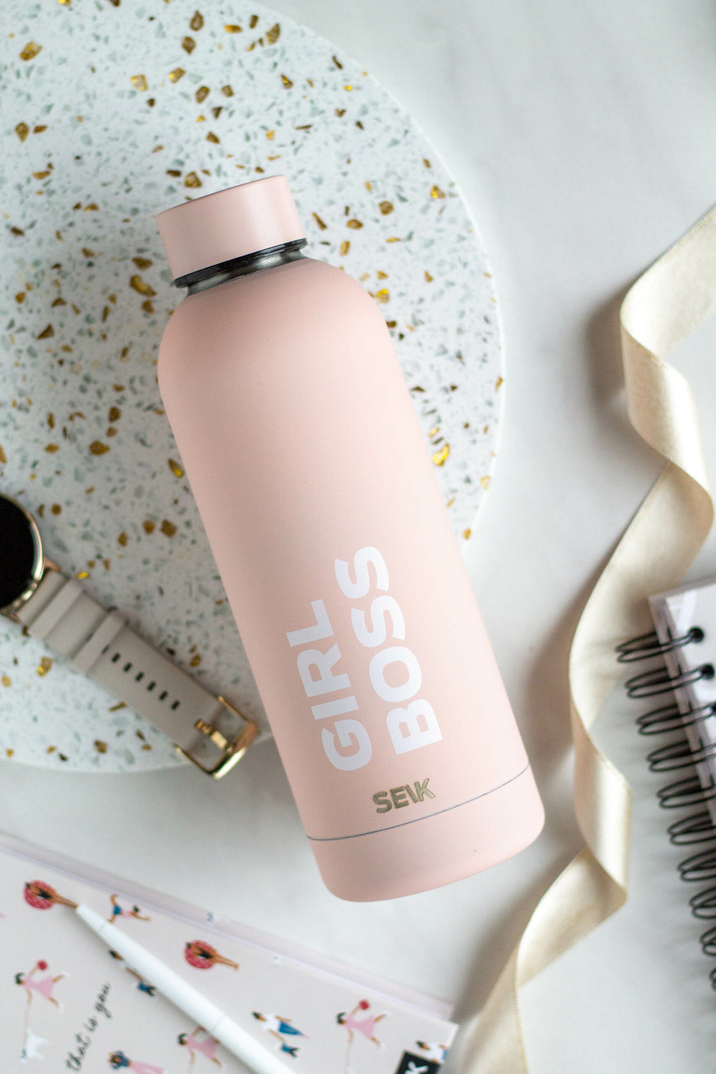 elegant seik girl boss thermos on a marble desk with a gold pen and notebook