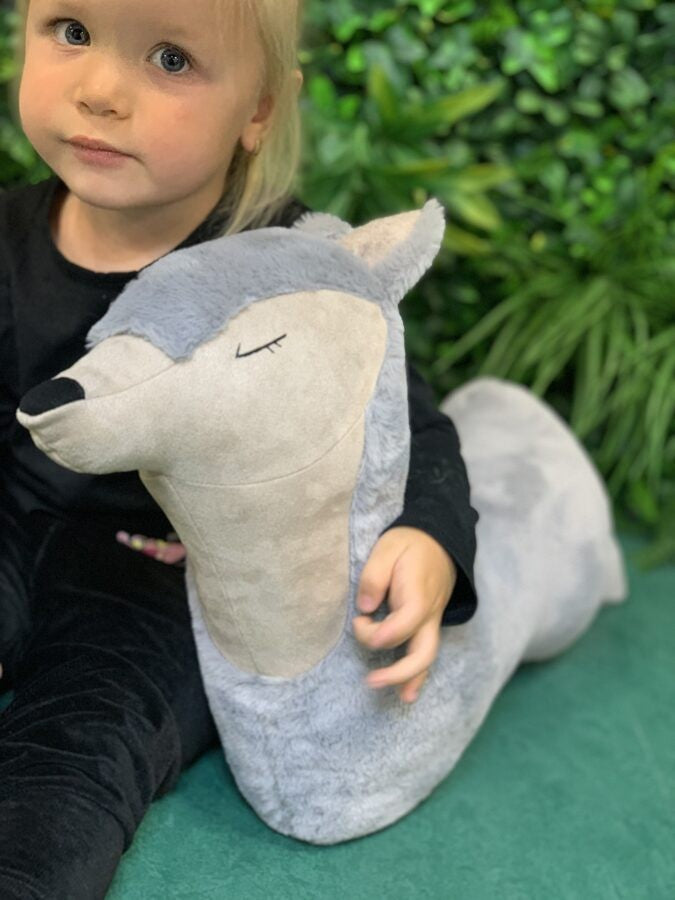 grey wolf pillow toy in soft morning light on a rustic wooden floor