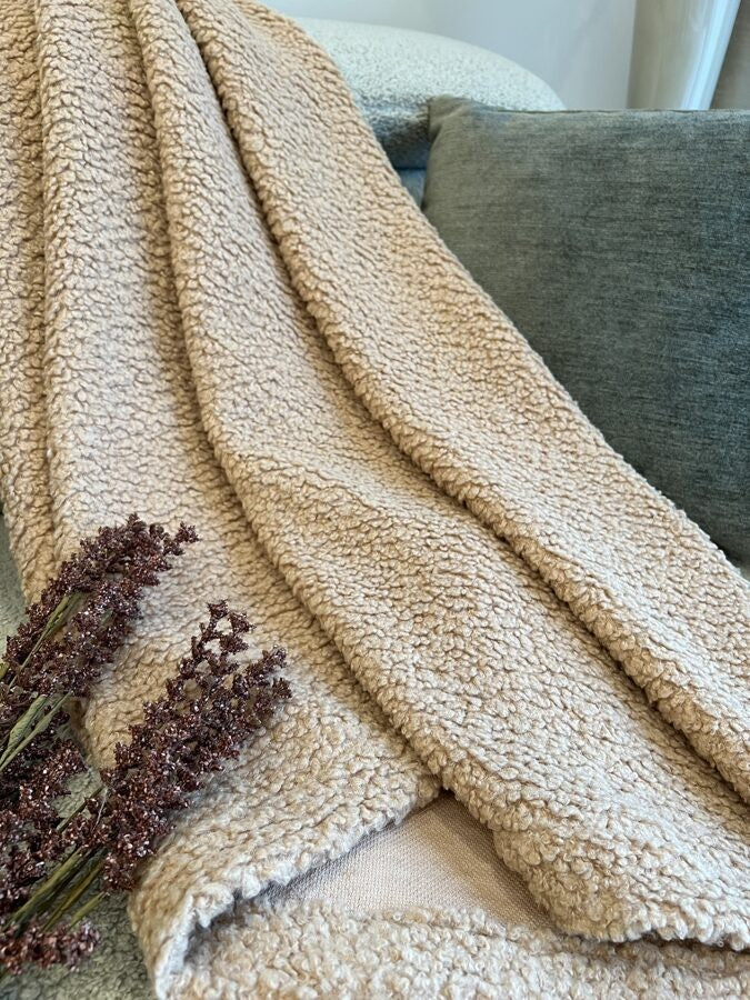 sand-coloured teddy blanket draped elegantly over a minimalist bed frame