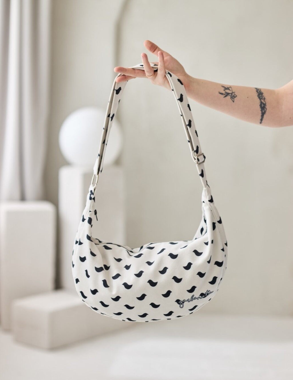 elegant women's velour hobo bag with a delicate birds design, shown in soft golden-hour lighting