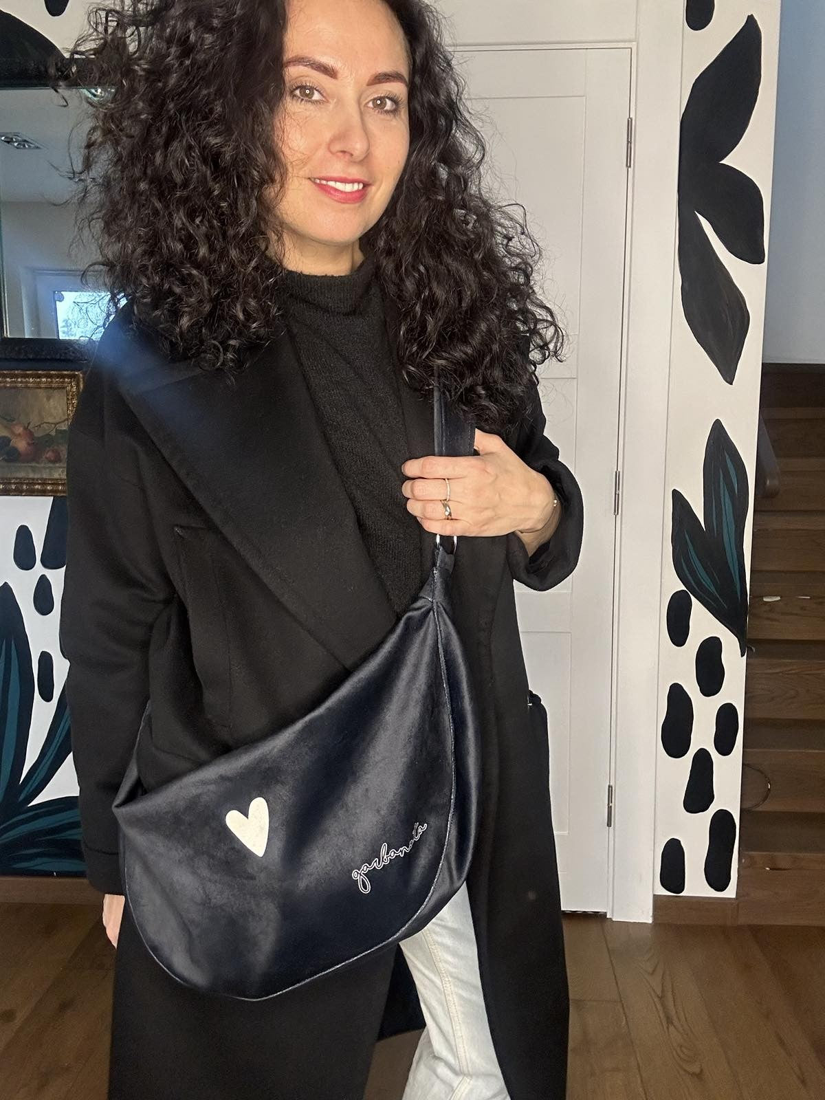 soft black velour hobo bag resting gently on a cozy surface, its slouchy form inviting a comforting touch