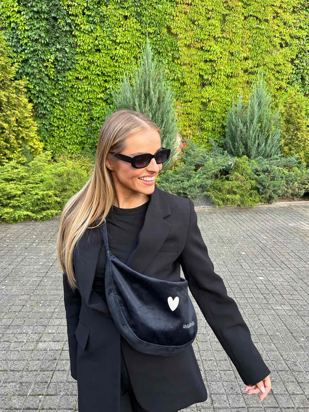 confident woman modeling a chic black velour hobo bag with a bold, slouchy silhouette