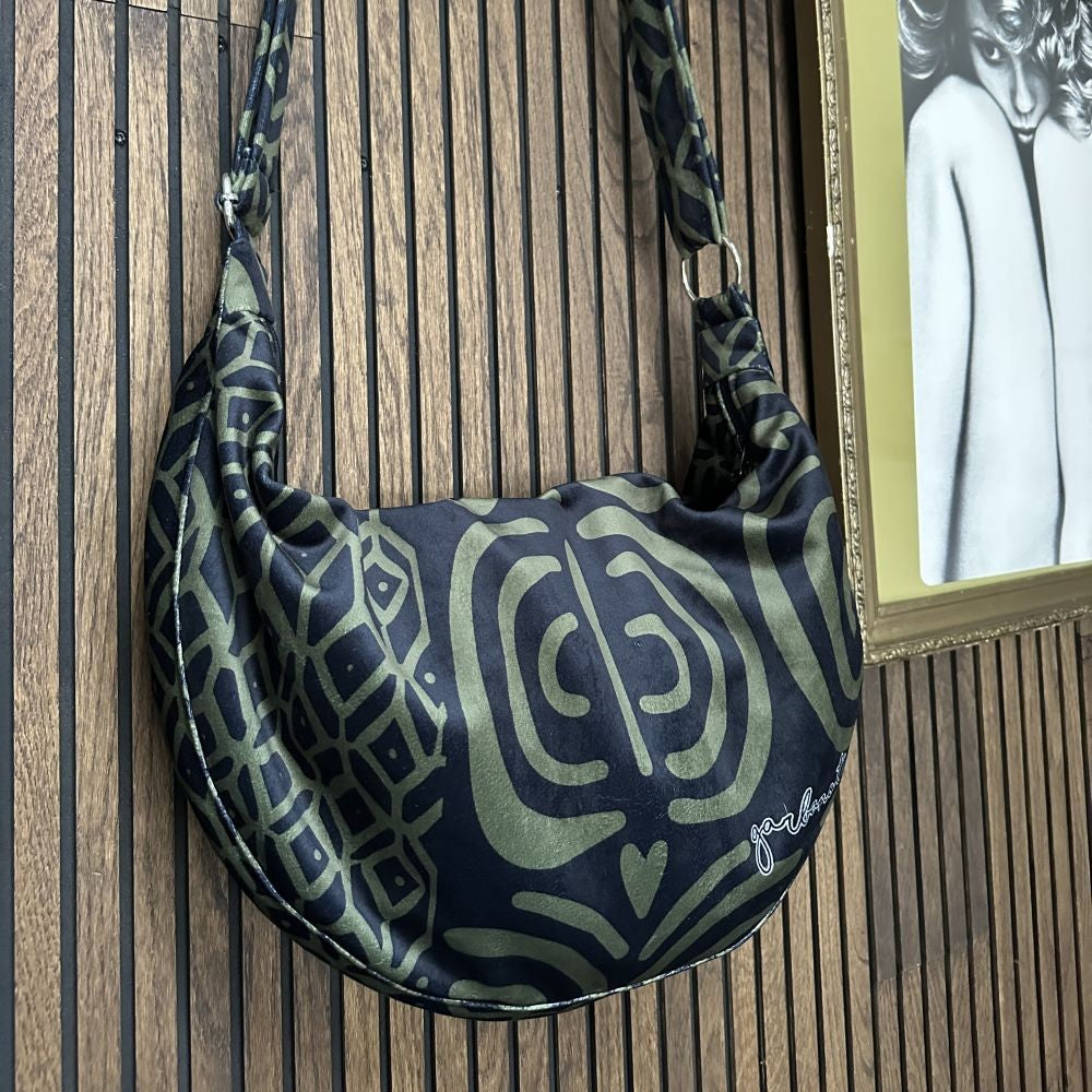 side view of a khaki velour hobo bag showing its spacious interior and adjustable shoulder strap