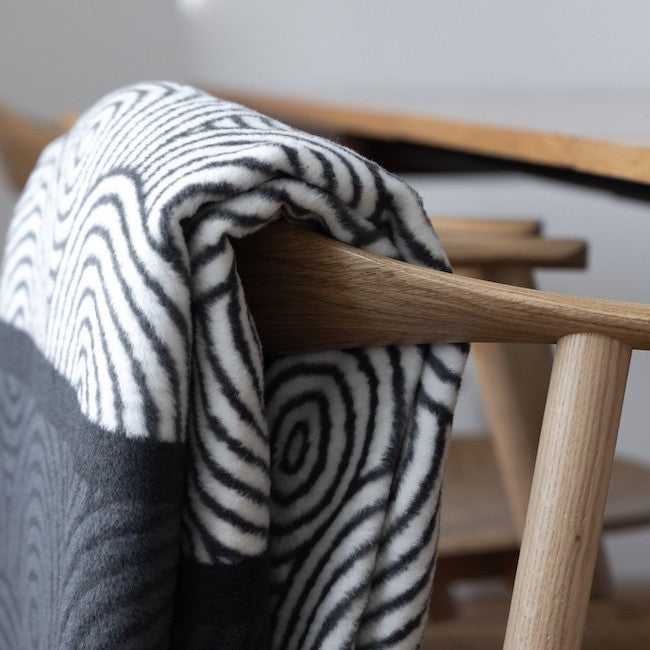 bold gray and white patterned huma blanket for pets on a dark modern sofa