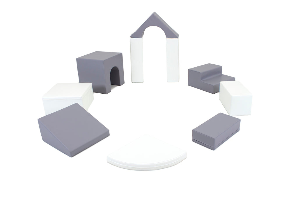a child's hand stacking a grey and white iglu foam block into a wobbly tower