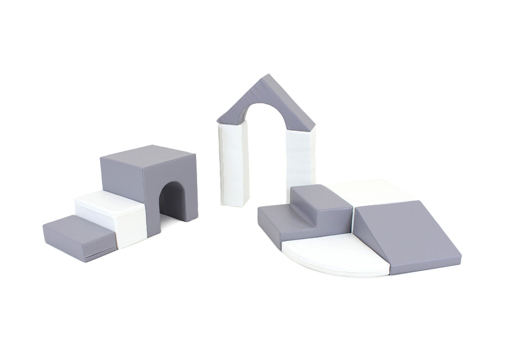 a child's small hands building a tall tower with grey and white iglu foam blocks