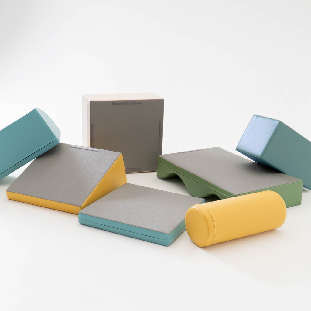 child building a wobbly pastel turquoise foam block tower on a playroom rug