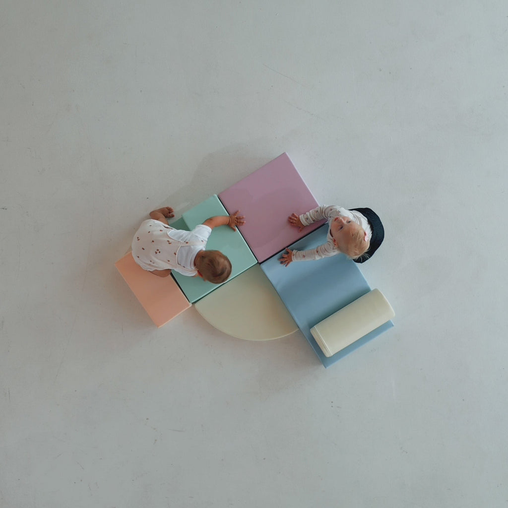a toddler building a cozy pastel igloo fort with soft foam blocks
