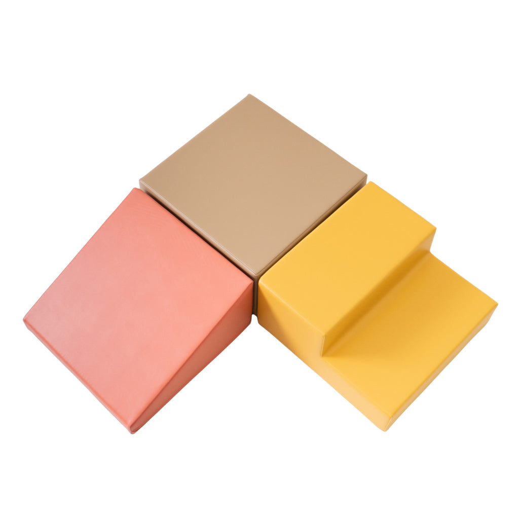 a toddler's hand reaching for a soft pink foam climbing block in warm morning light