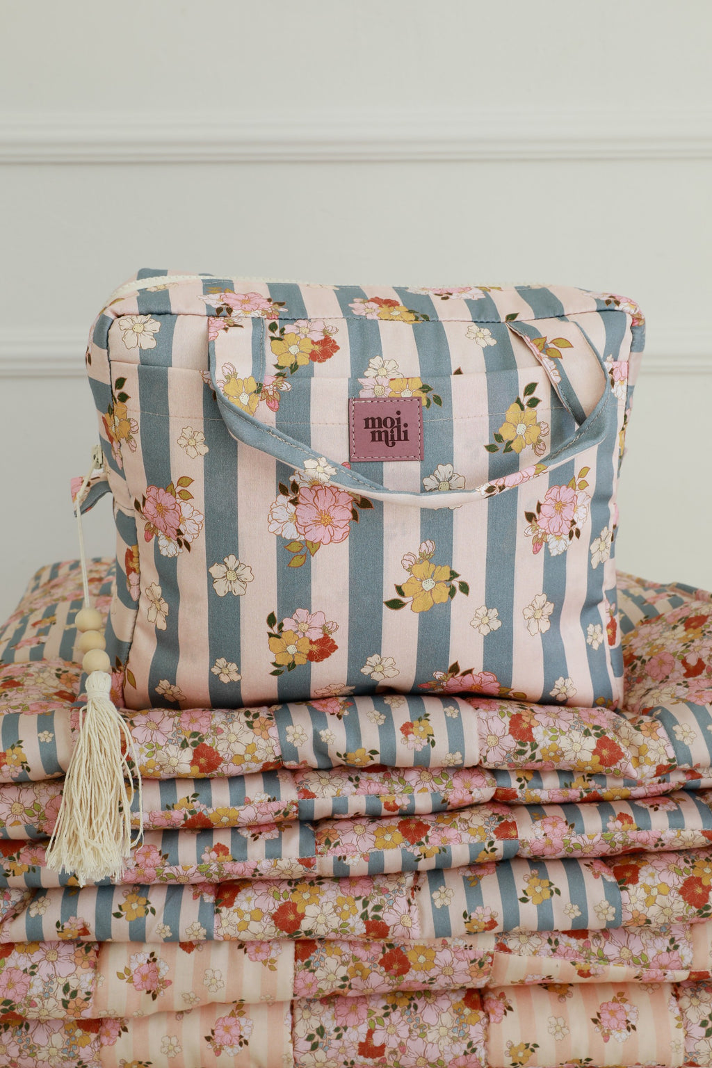 soft blue striped cotton makeup bag set open on a cozy bed, showing its spacious waterproof interior