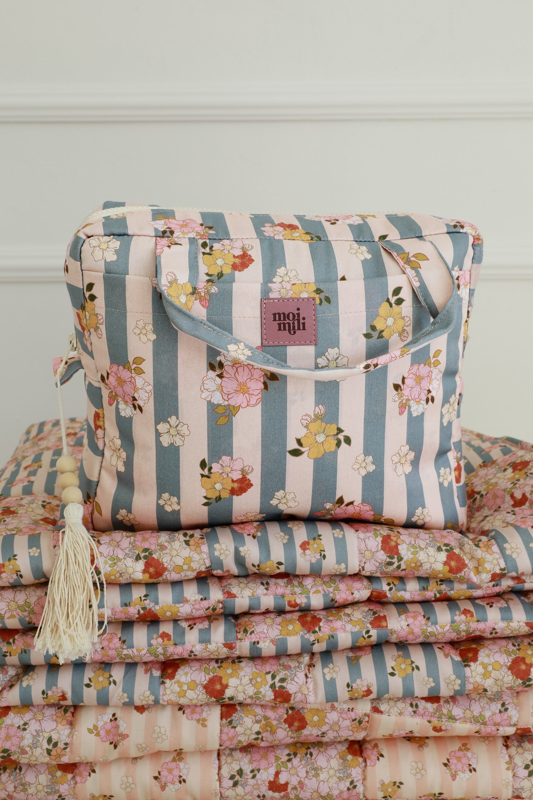 soft blue striped cotton makeup bag set open on a cozy bed, showing its spacious waterproof interior