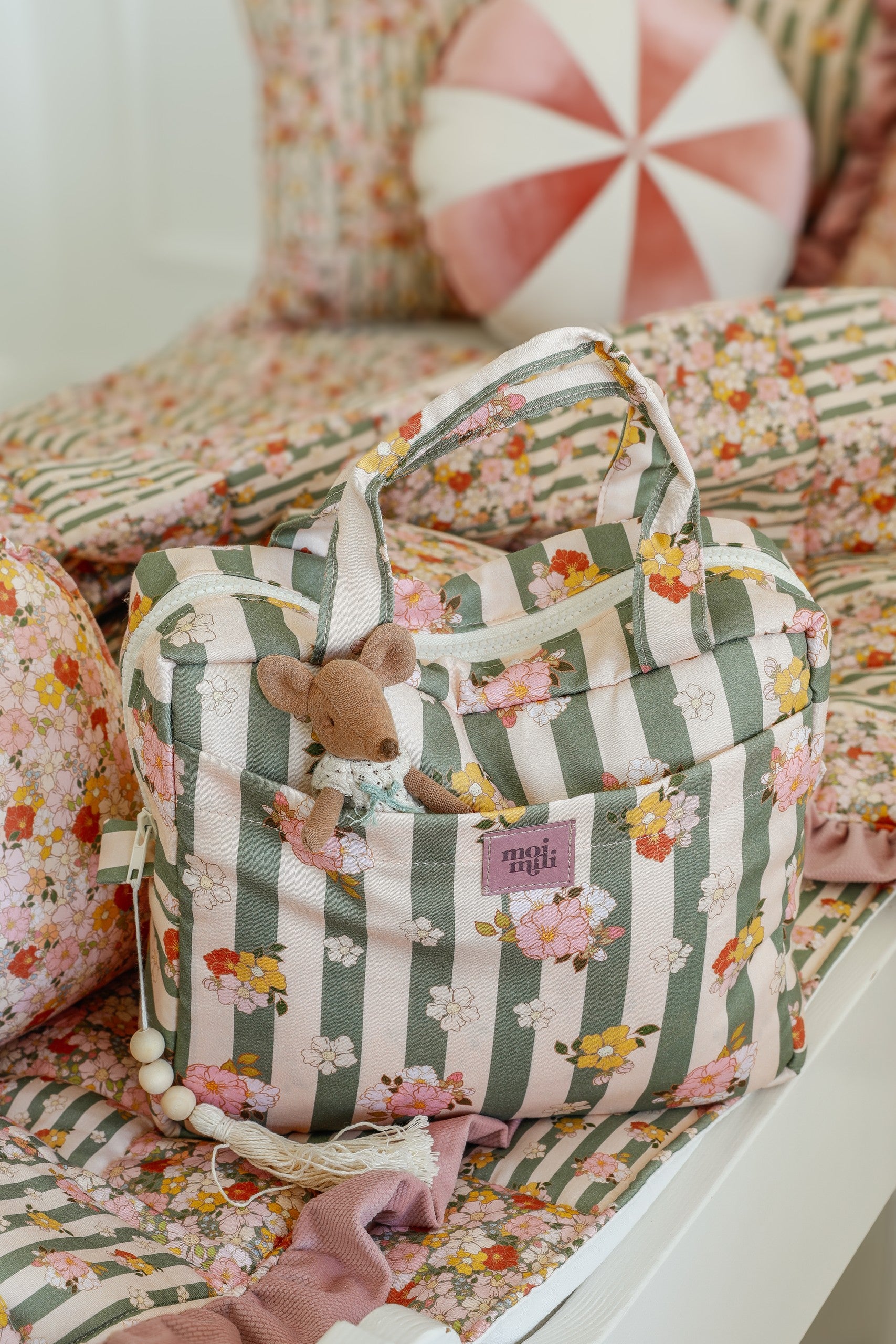a playful close-up of the chic striped makeup bag open on a sandy beach, showing its colorful interior pockets
