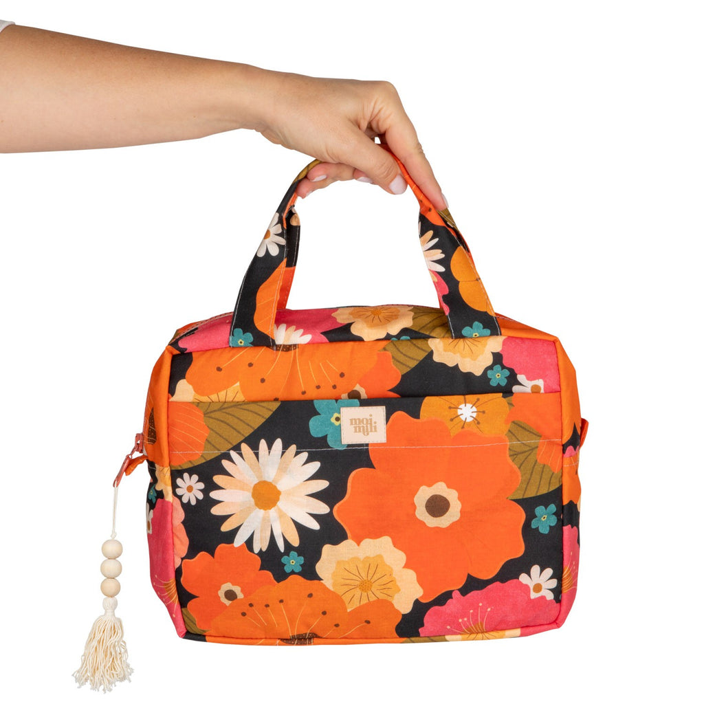 bold floral makeup bag open on a rustic table revealing its waterproof lining and pockets