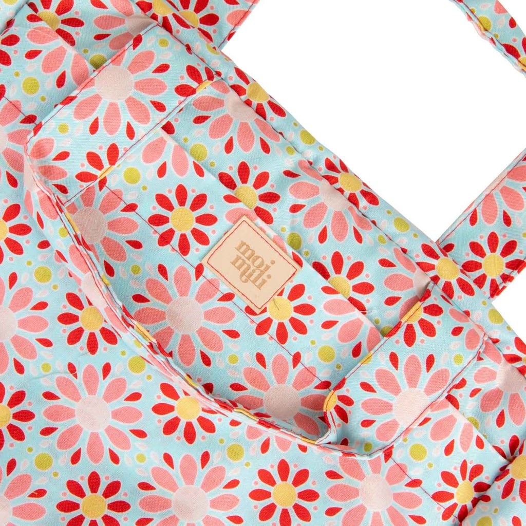 soft red floral makeup bag with waterproof lining, open to show inner pockets, resting on a cozy linen backdrop