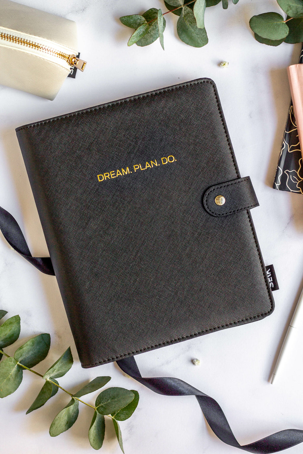 elegant vegan leather notebook lying open on a marble surface, showcasing its refined dot-grid pages and sophisticated design