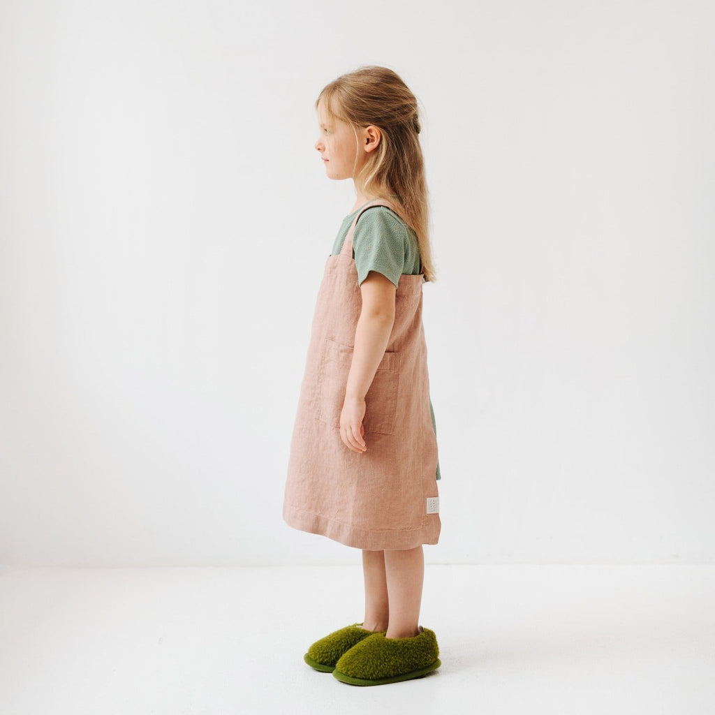 confident young chef in a honey linen pinafore apron standing proud in a sunlit kitchen