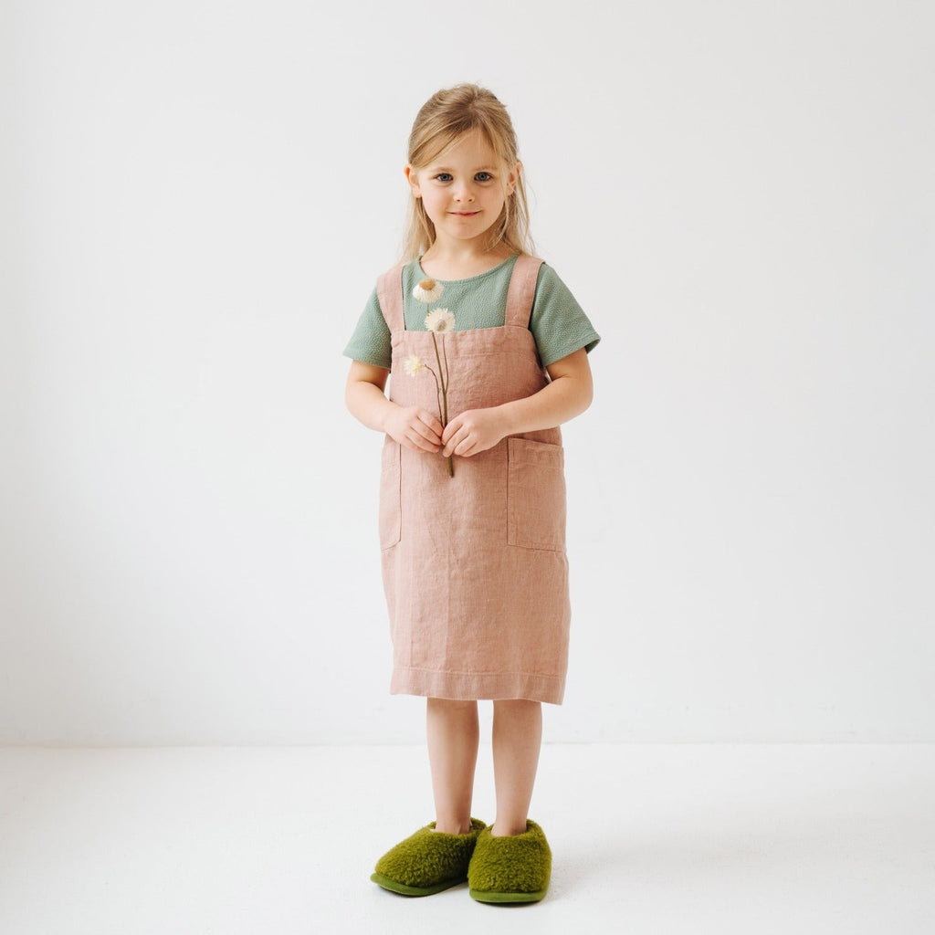 close-up of a child's linen apron pockets holding baking tools, showcasing its practical design