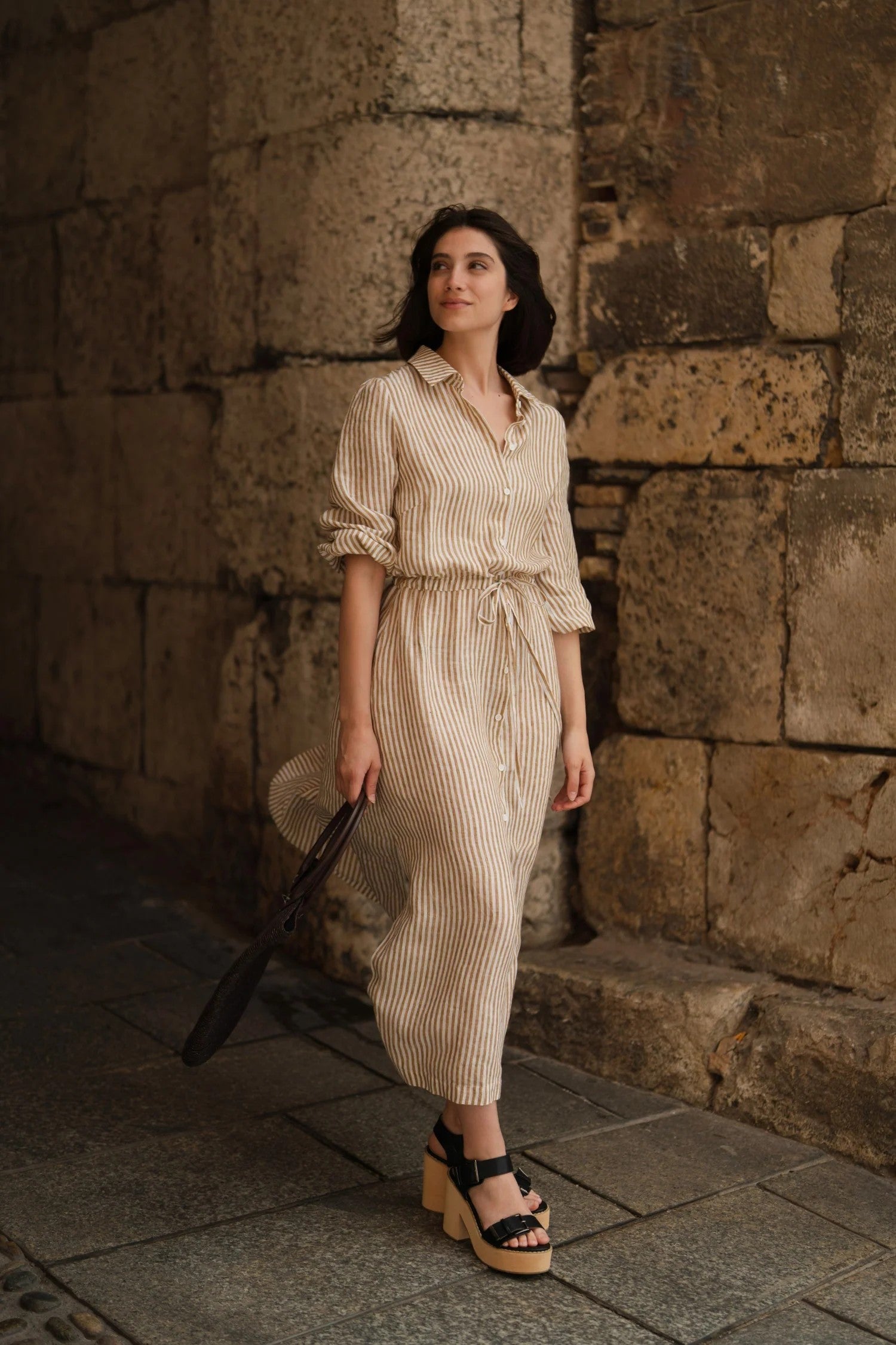 confident woman in bronze white striped linen dress with side splits, bold daytime look
