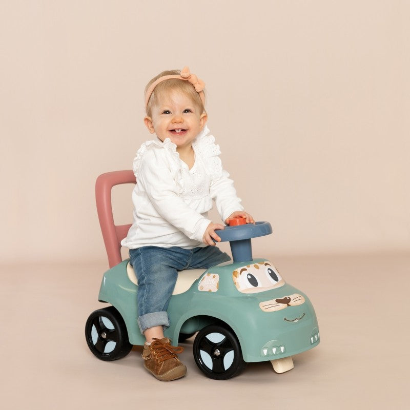 pastel ride-on pusher with horn, toddler pushing it on a sunny patio, learning to walk with joy