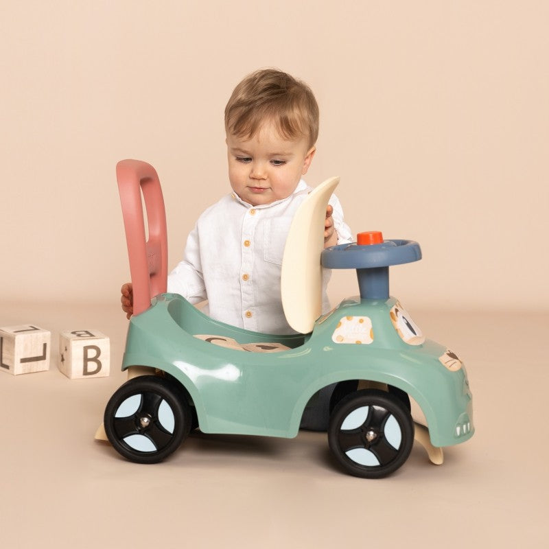pastel ride-on pusher with horn, seen from a playful low angle, highlighting its sturdy wheels and cozy seat