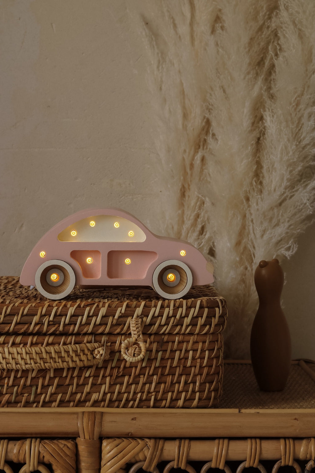 bold hero shot of the pinewood beetle car lamp glowing warmly on a dark wood surface