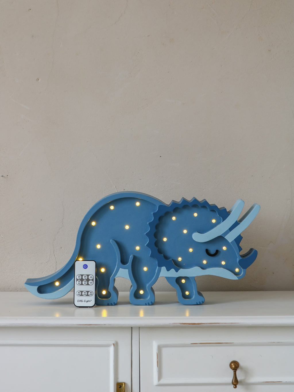handcrafted pine wood triceratops lamp casting a gentle glow on a nursery shelf