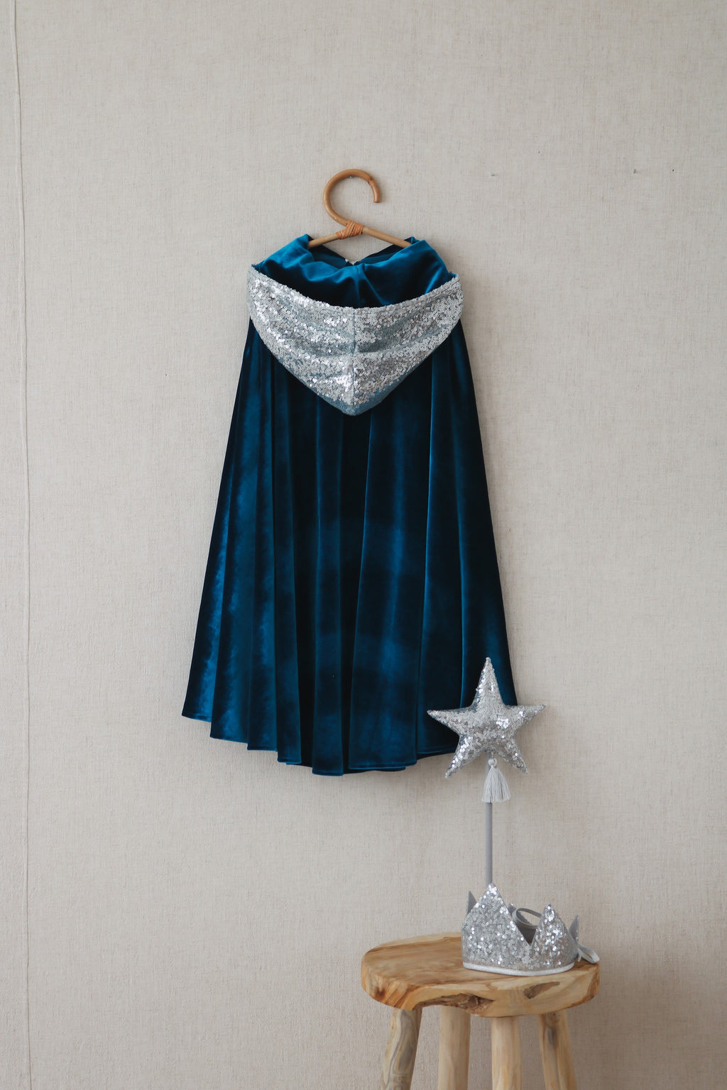 soft blue velour snow queen cape with a deep hood, shown from a gentle side angle in cozy indoor light