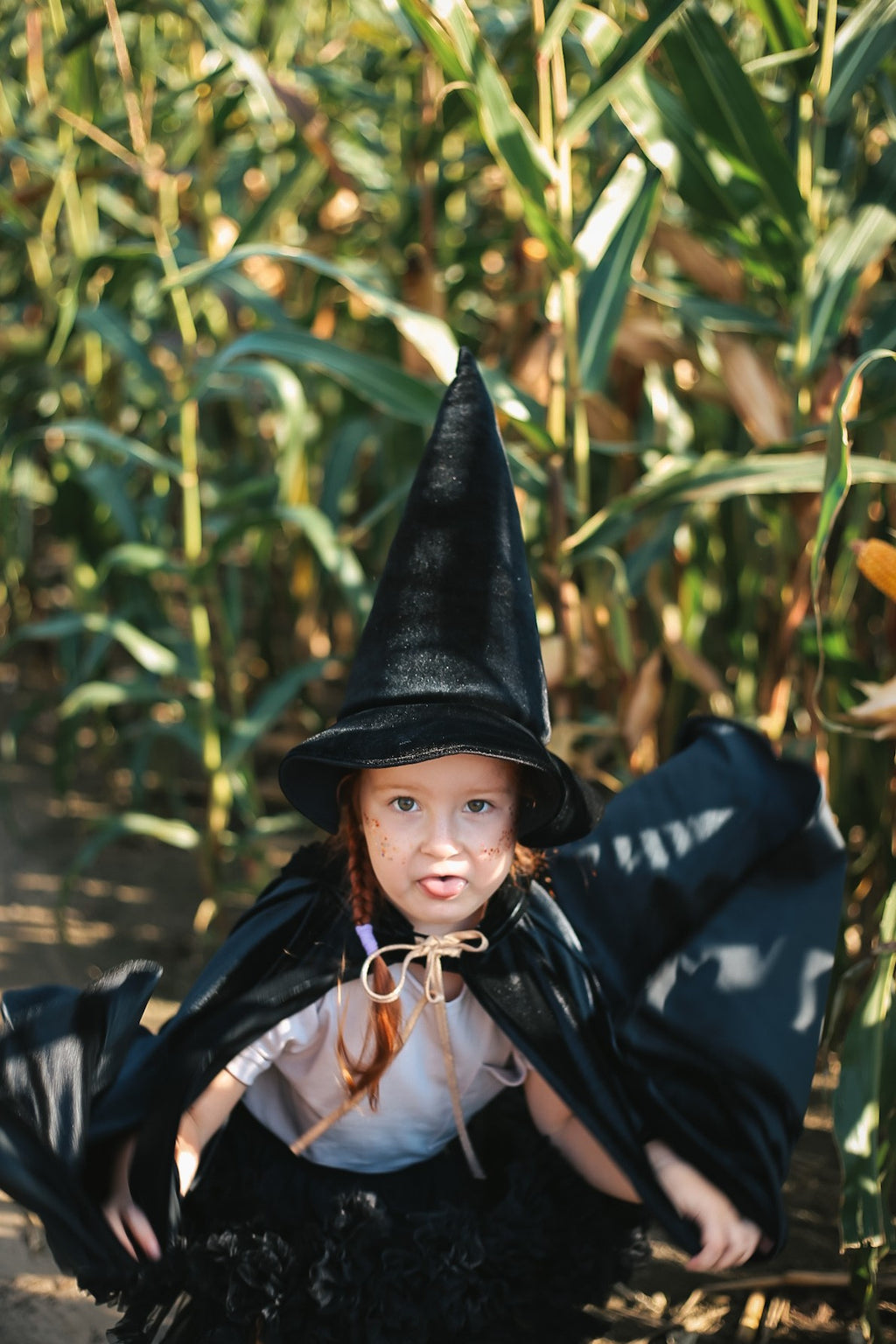 confident child in a bold black velour riding hood cape with a deep hood and snap fastening