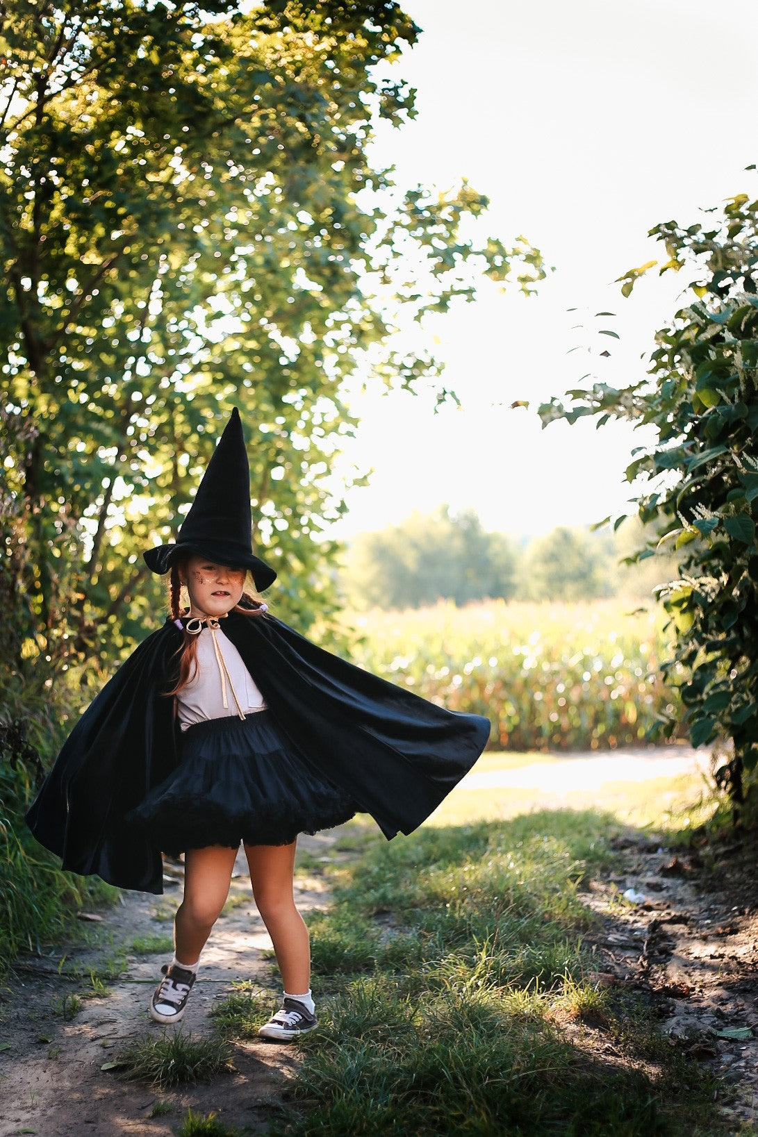 practical view of black velour riding hood cape showing secure snap closure and hand holes for active play