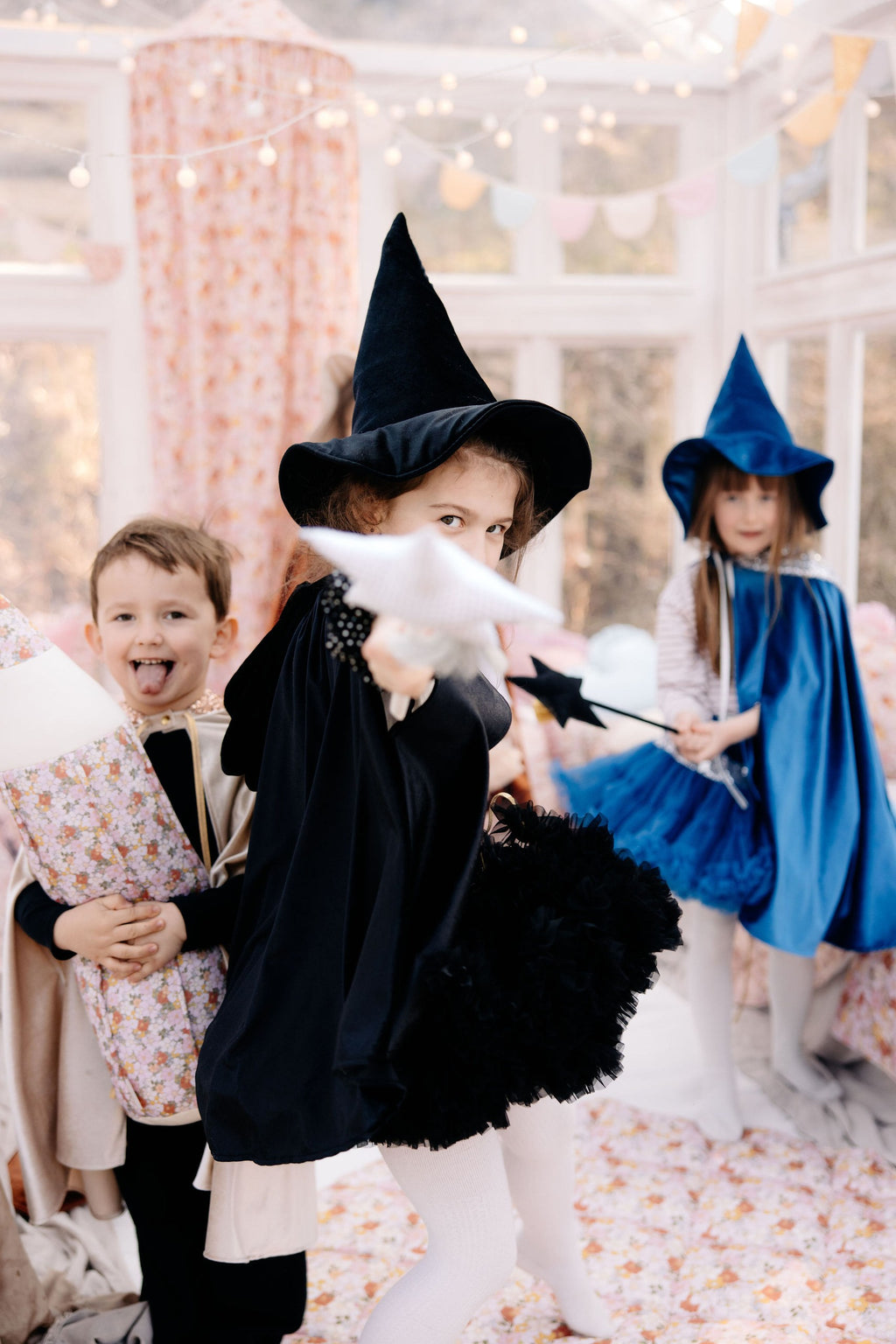 child in a black velour hooded cape casting a shadow in a mystical forest