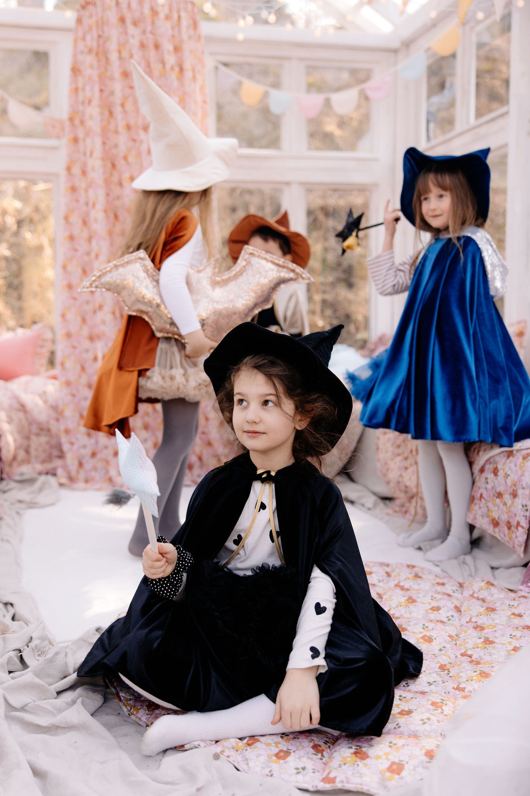 a child's hand peeking from the hand hole of a soft black velour cape