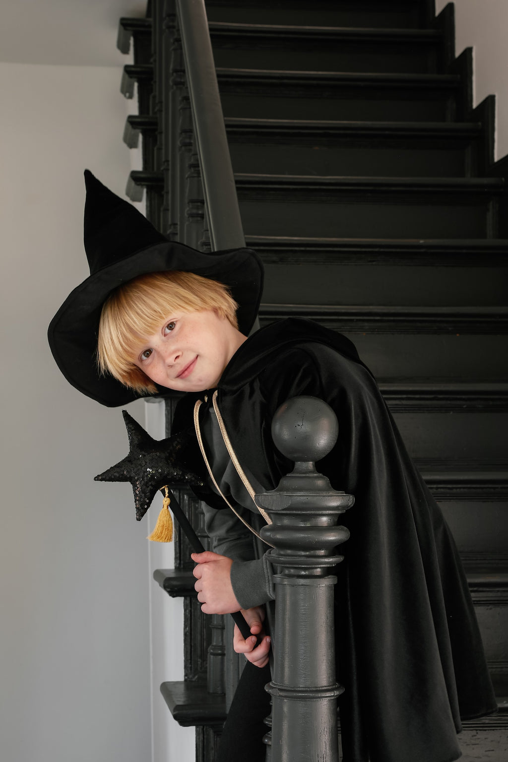 child in a black velour hooded cape twirling in a sunlit garden adventure