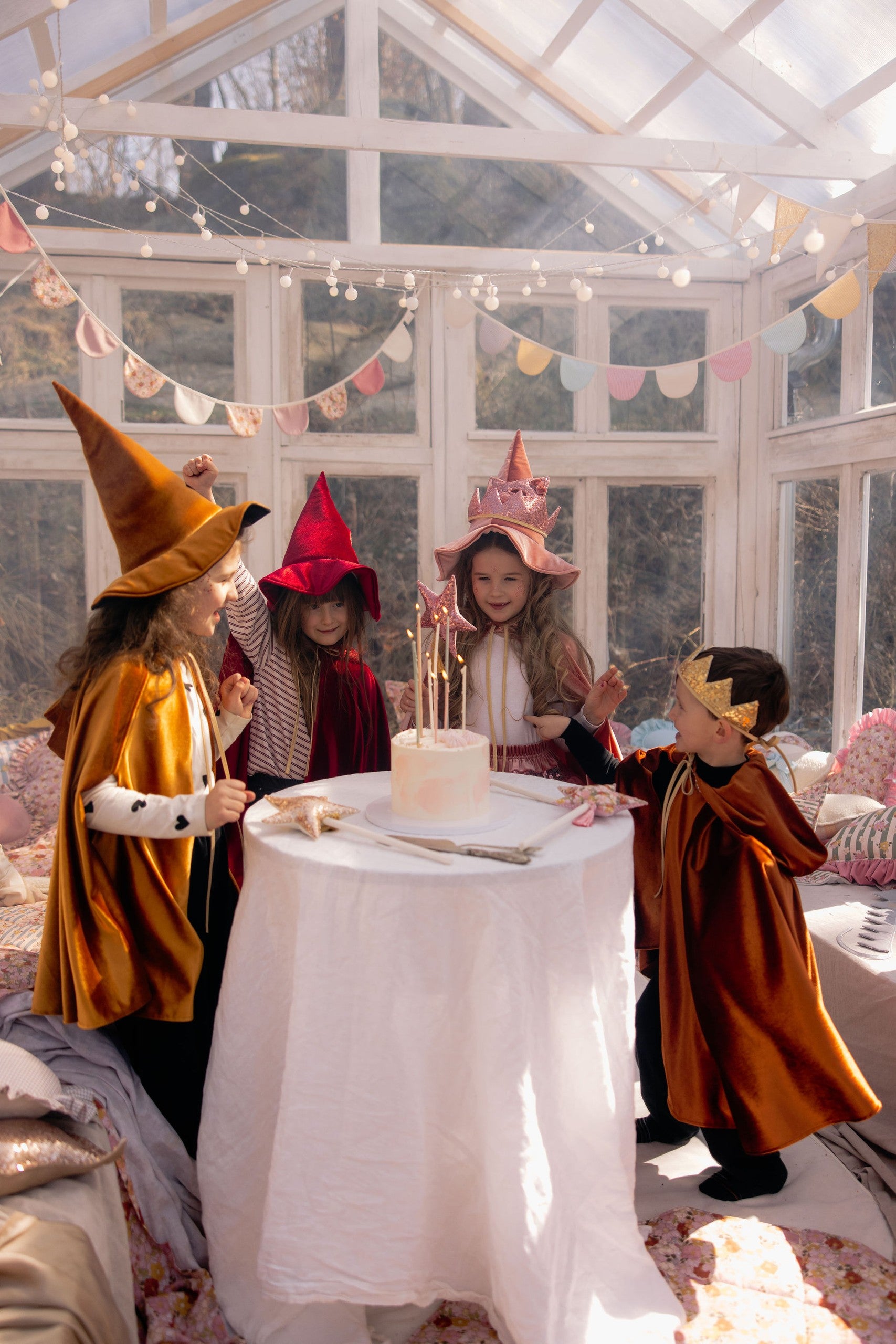 child in a ginger velour cape twirling in a sunlit garden, hood up and arms outstretched for magical play