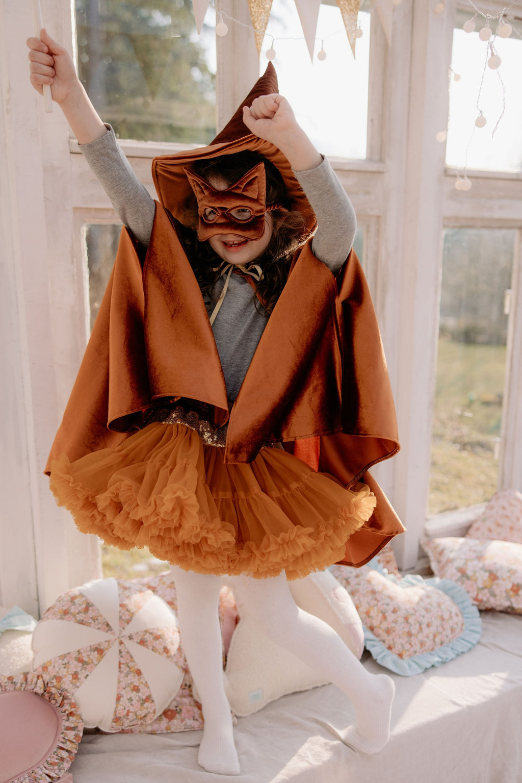 child in a ginger velour cape twirling to show the swish of the fabric