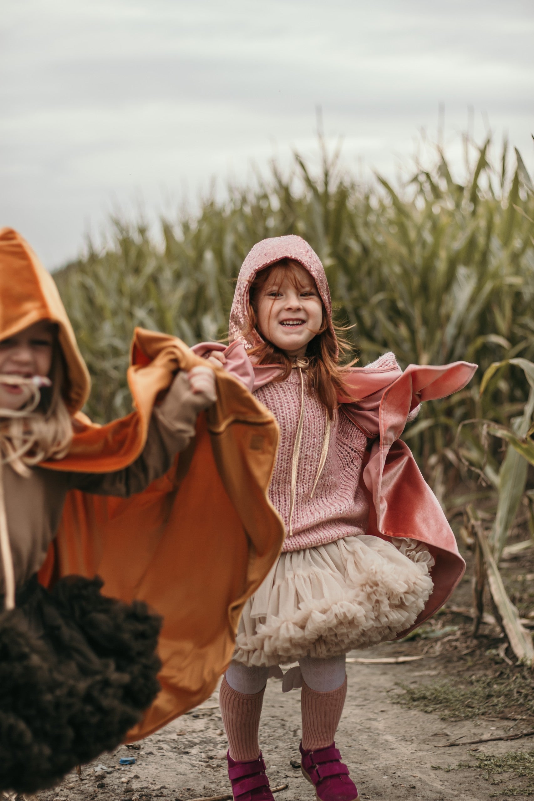 pink velour riding hood cape showing snap fastenings and secure laces for active play