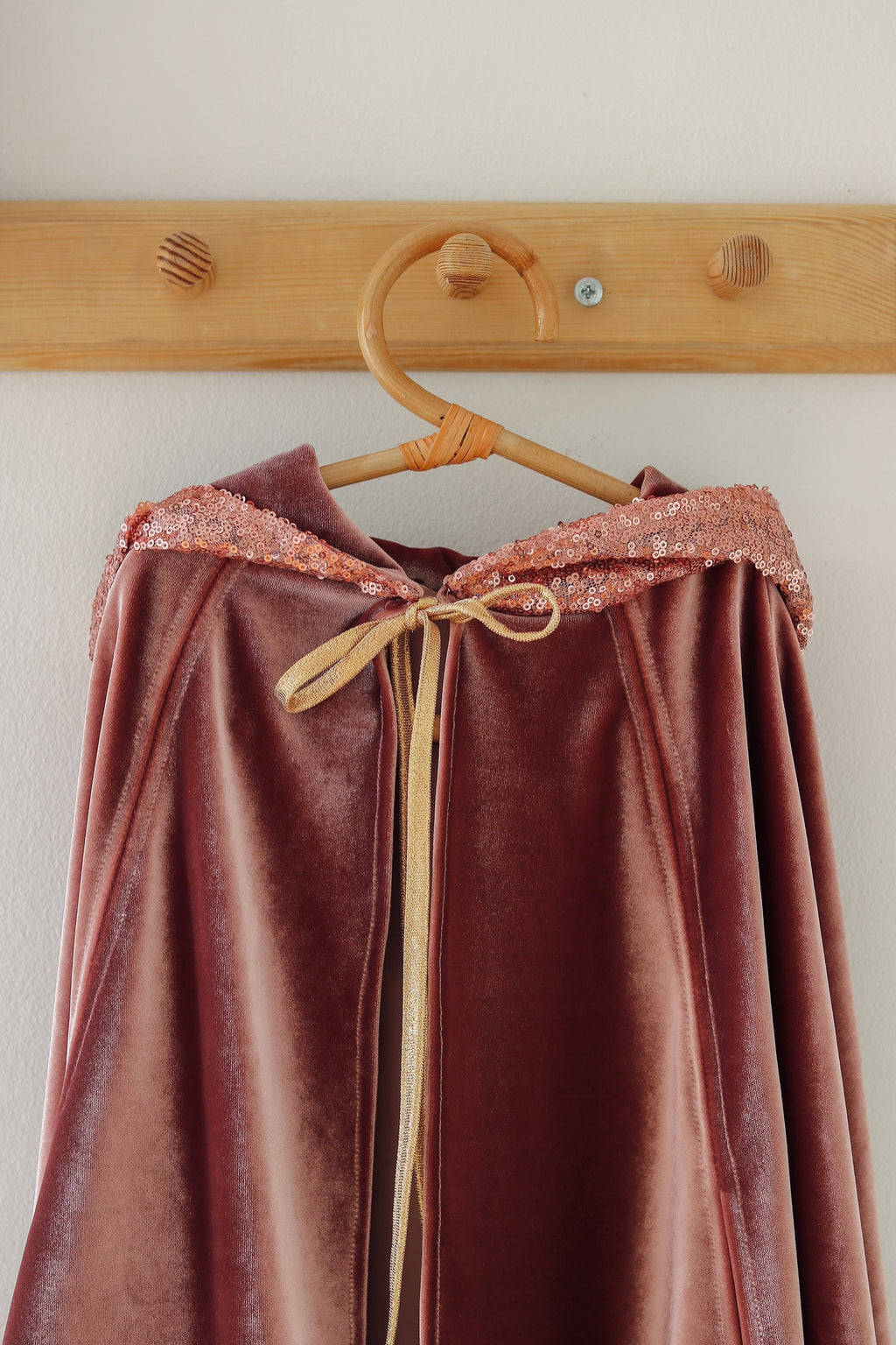 a child in a pink velour hooded cape playing outdoors on a sunny day