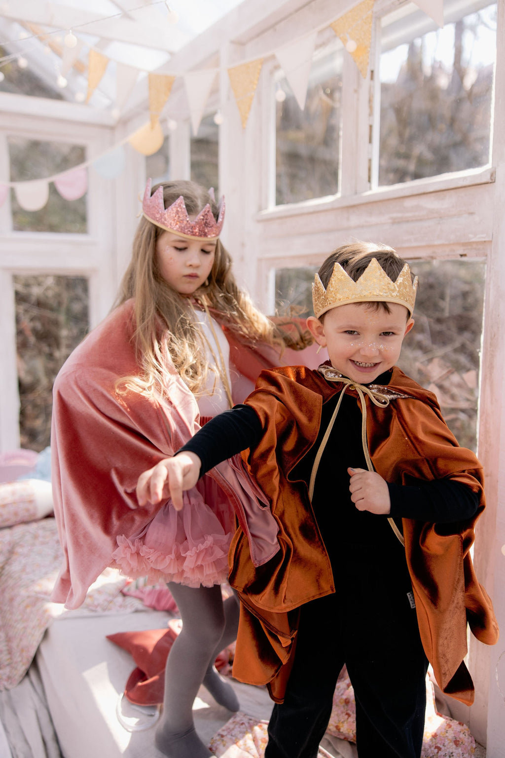 a child's hand holding the corner of a shimmering pink velour hooded cape